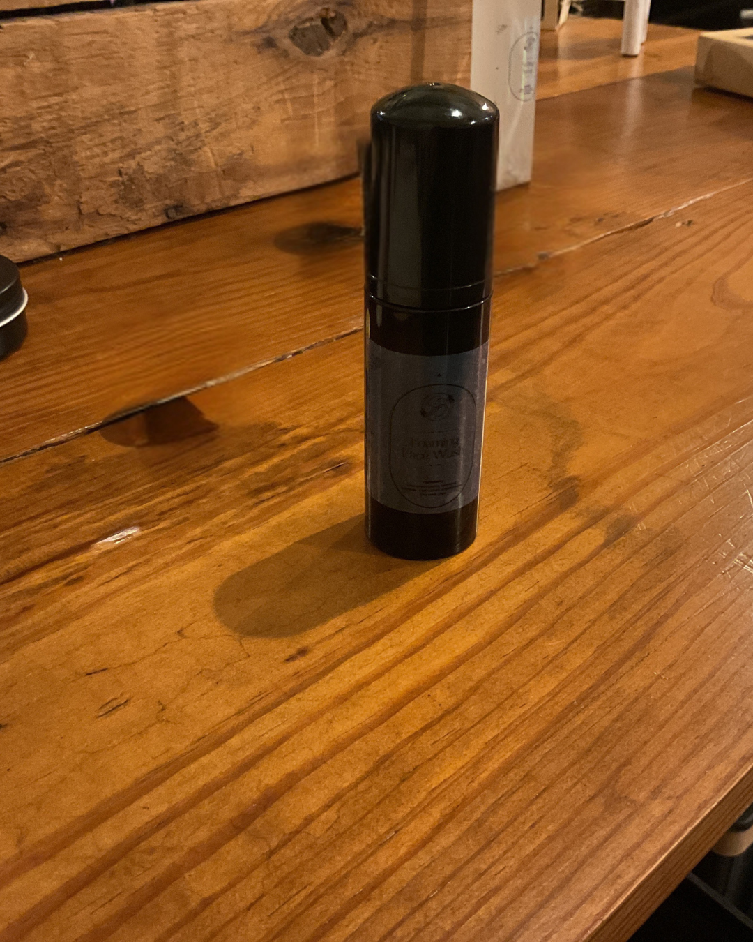 Black cylindrical bottle on a wooden surface