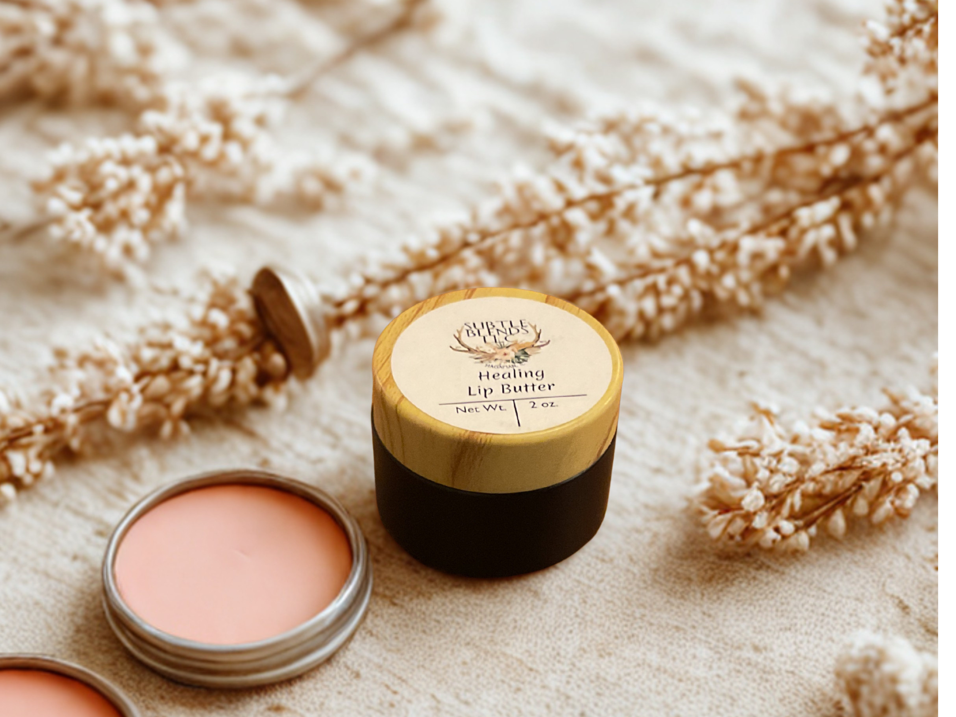 Lip balm containers on a textured surface with dried flowers