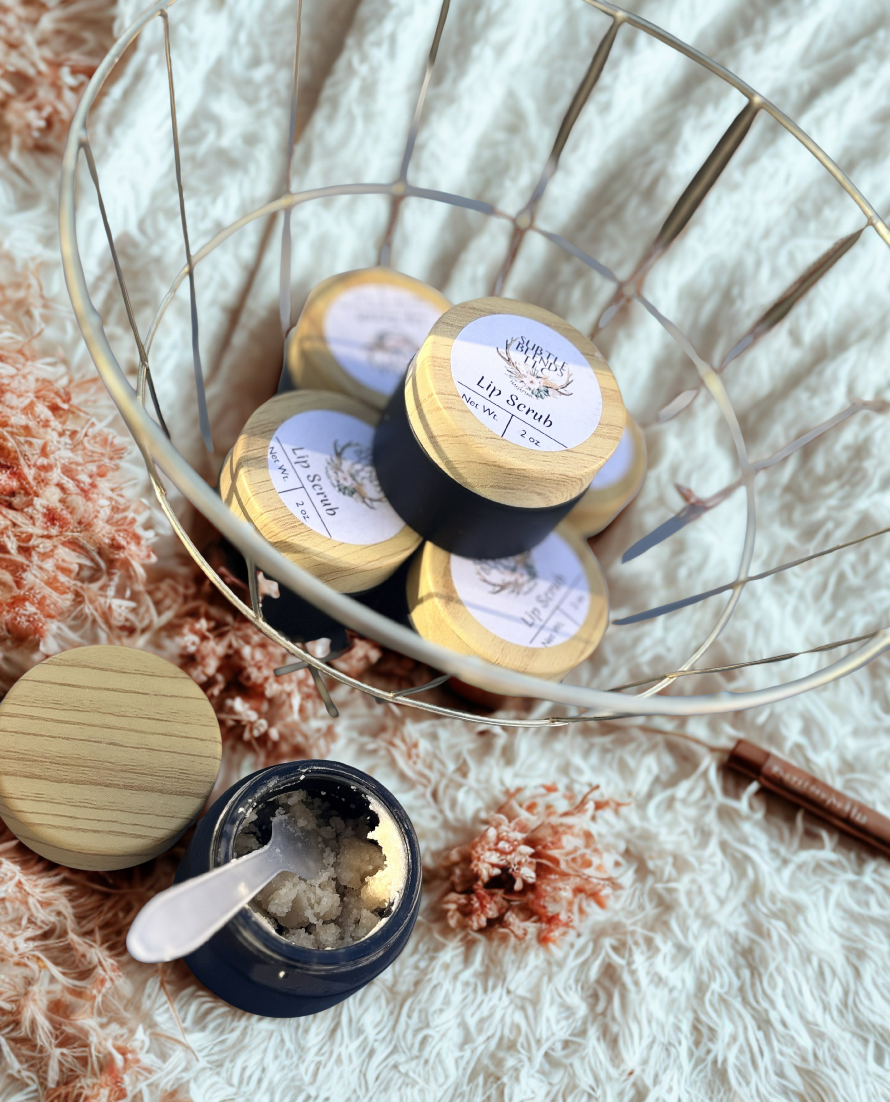 Lip scrub containers with wooden lids on a textured surface