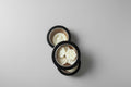Black containers with white flower-shaped objects on a textured surface