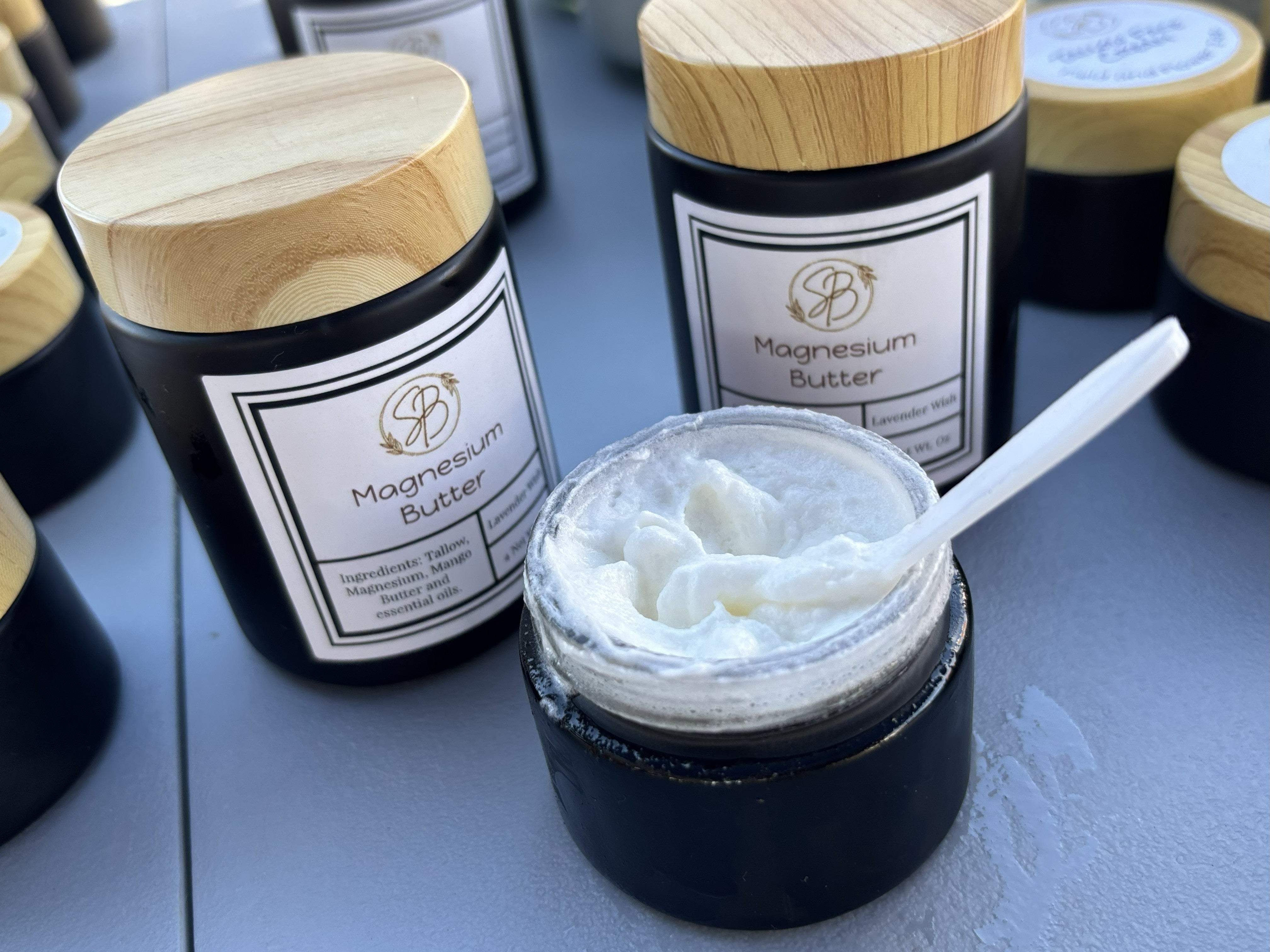 Jars of magnesium butter with wooden lids on a gray surface