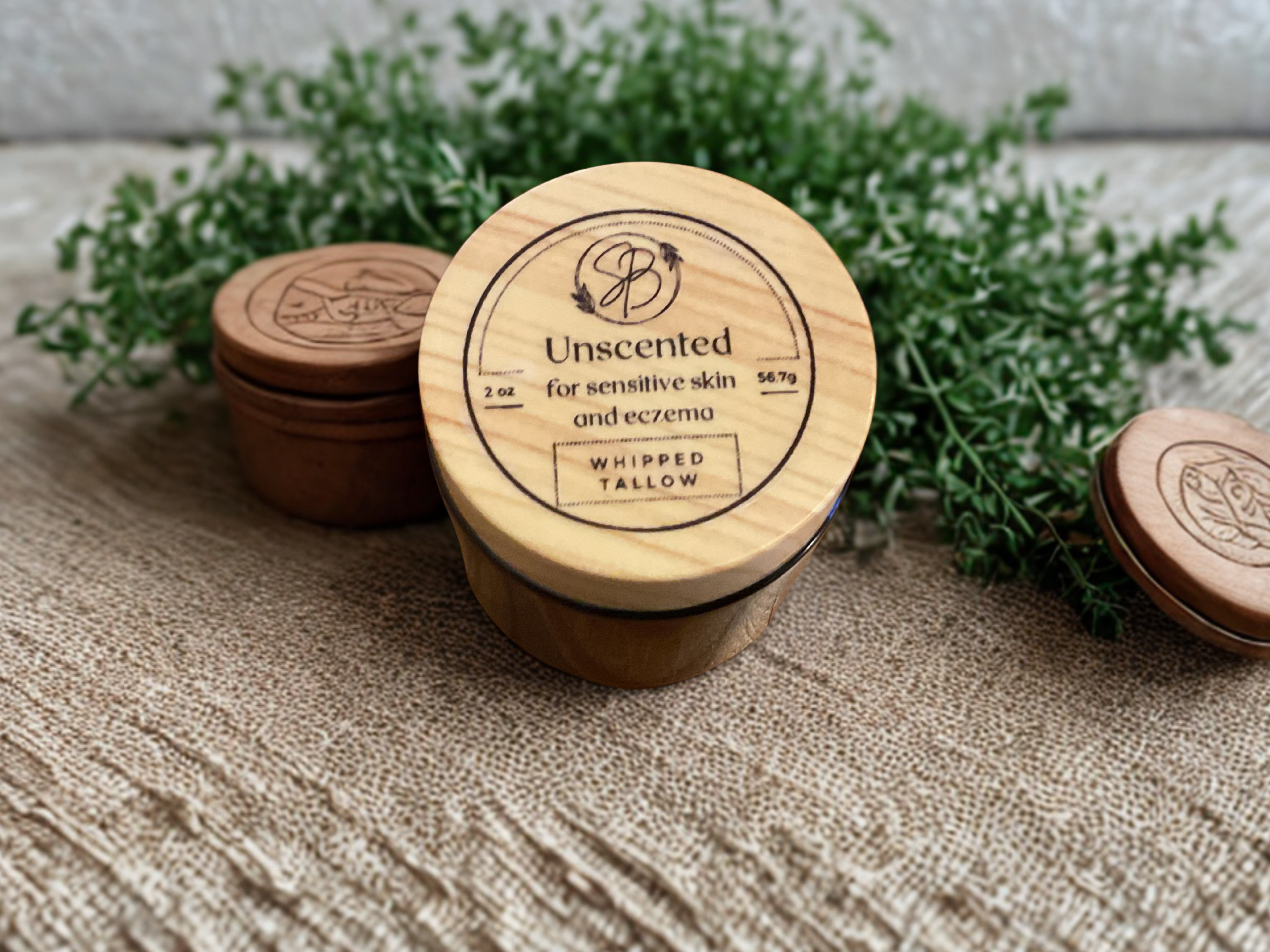 Wooden containers with lids on a textured surface with greenery in the background